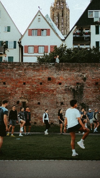 Eine Gruppe von Läufern, die sich an der Stadtmauer in Ulm dehnt. Gemeinsames Aufwärmen vor dem Laufen beim Runclub in Ulm.