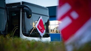Eine ver.di-Fahne hängt an einem geparkten Linienbus.