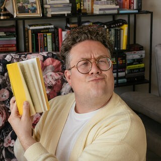 Thomas Bookclub hält ein Buch.