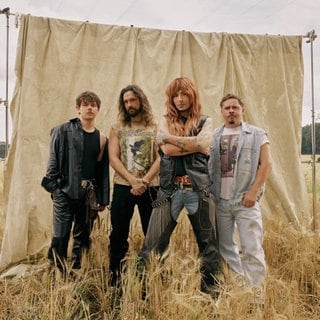 Tokio Hotel vor einer Leinwand  in einem Feld stehend